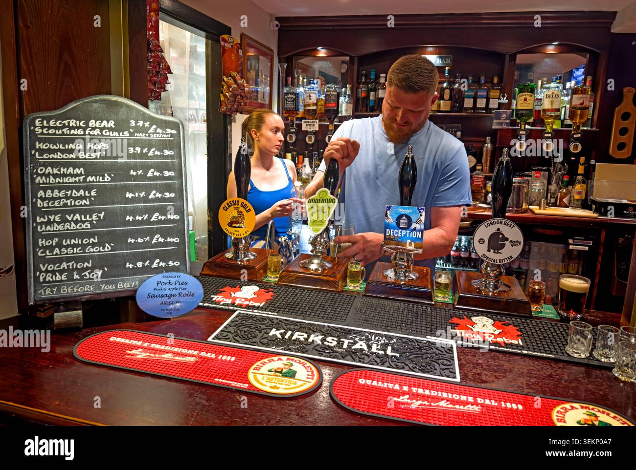 ATVH real ale bar staff pulling pints behind a traditional pub counter in Britain, UK. Stock Photo