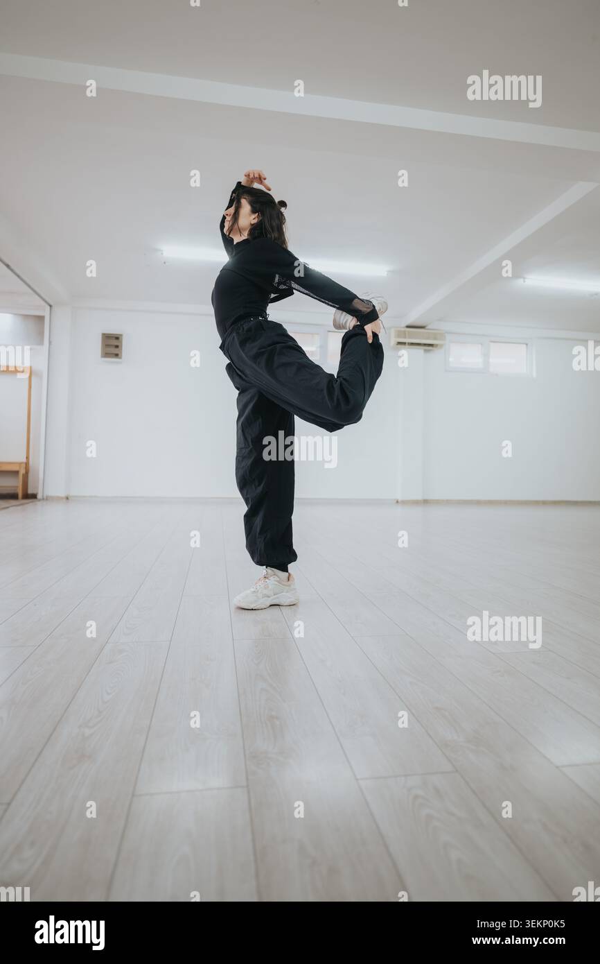 Female dancer stretching in a bright studio practicing a balancing contemporary dance pose Stock Photo