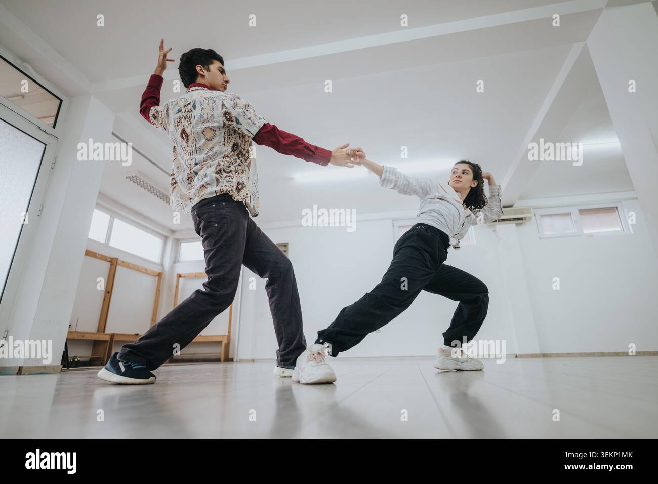 Two dancers practicing a contemporary partner routine in a bright empty studio space Stock Photo