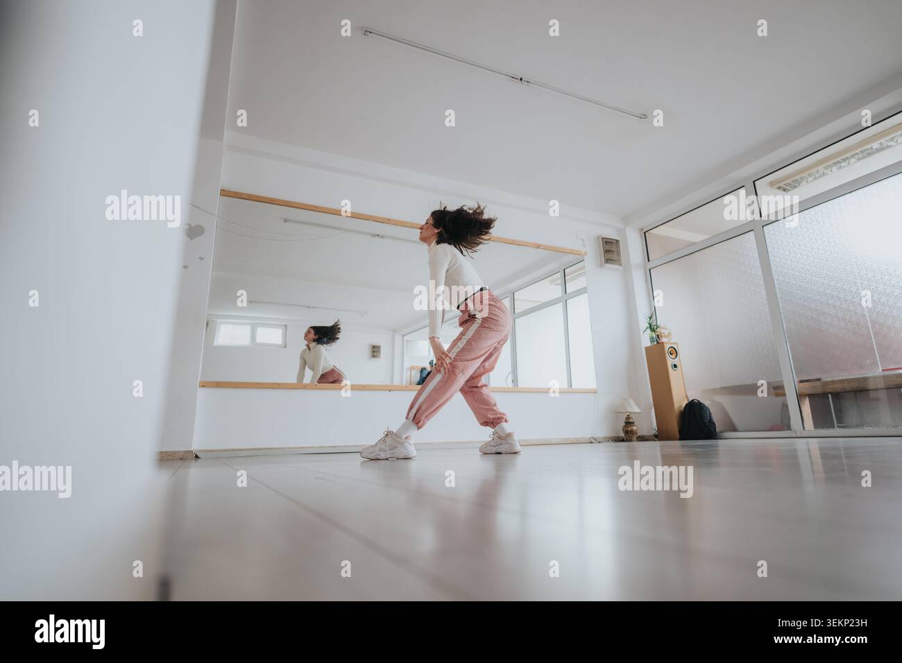 Young dancer practicing energetic choreography in a bright modern dance studio with mirror Stock Photo