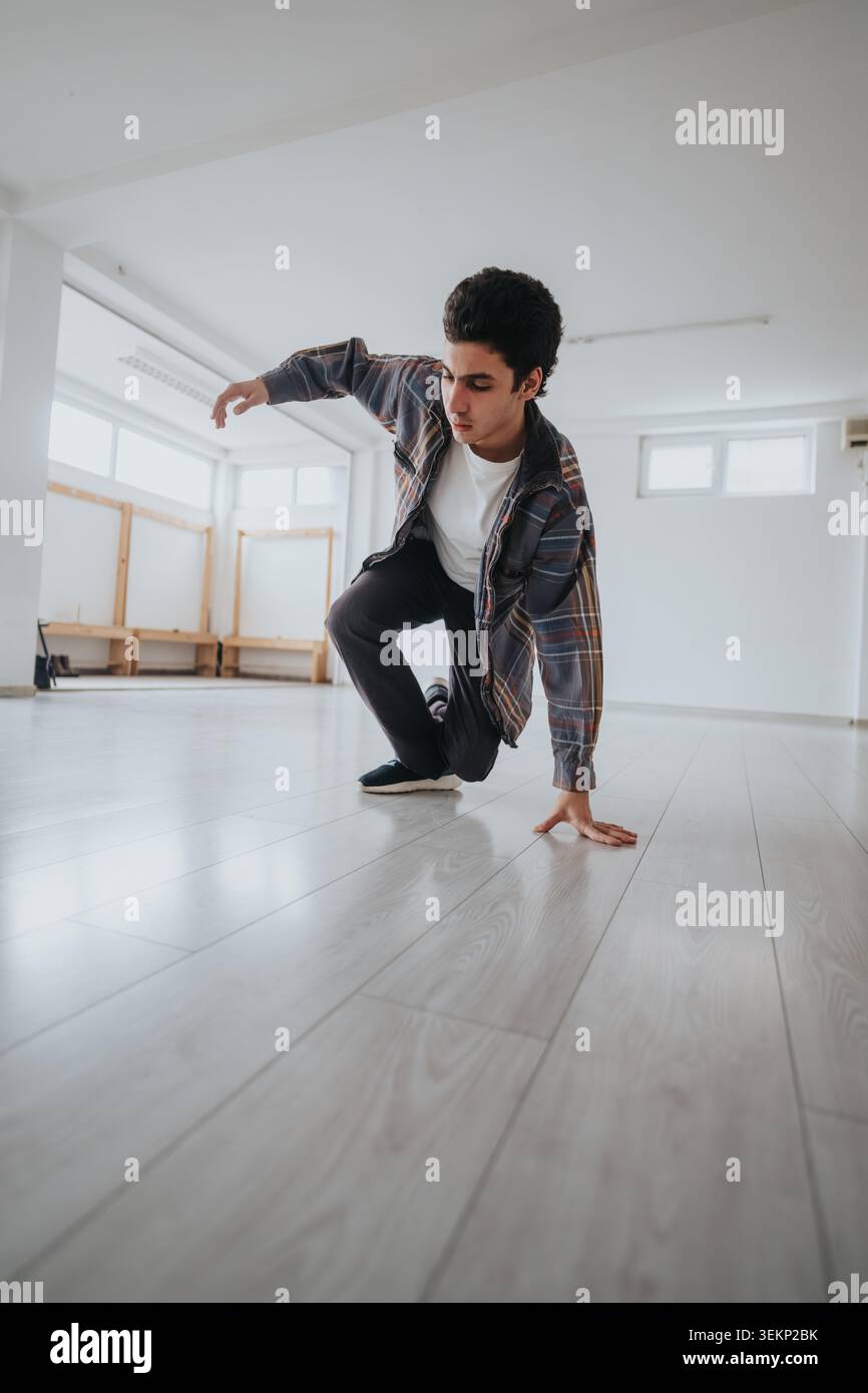 Young male dancer practicing a break dance move alone in a bright empty dance studio space Stock Photo