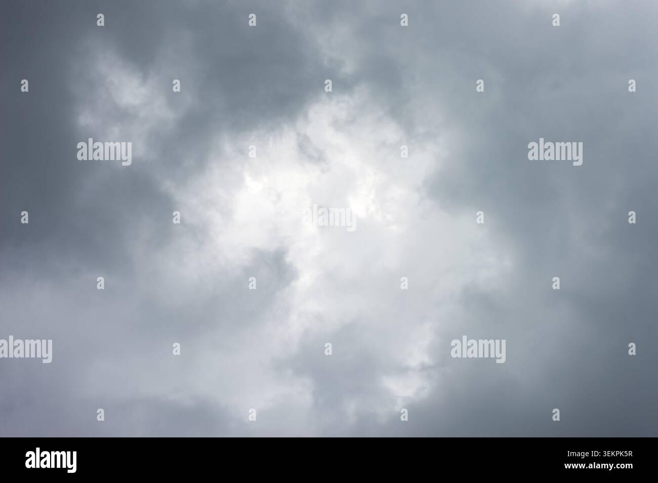 A dramatic and moody view of dark, overcast storm clouds gathering in the sky, with a slightly brighter center Stock Photo