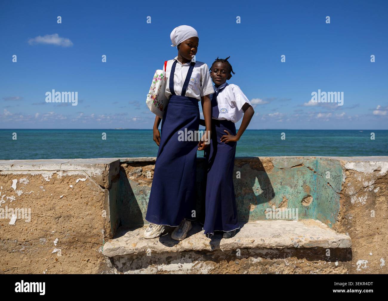 Girls standing on a bench in front of the sea, Nampula Province, Island of Mozambique, Mozambique Stock Photo