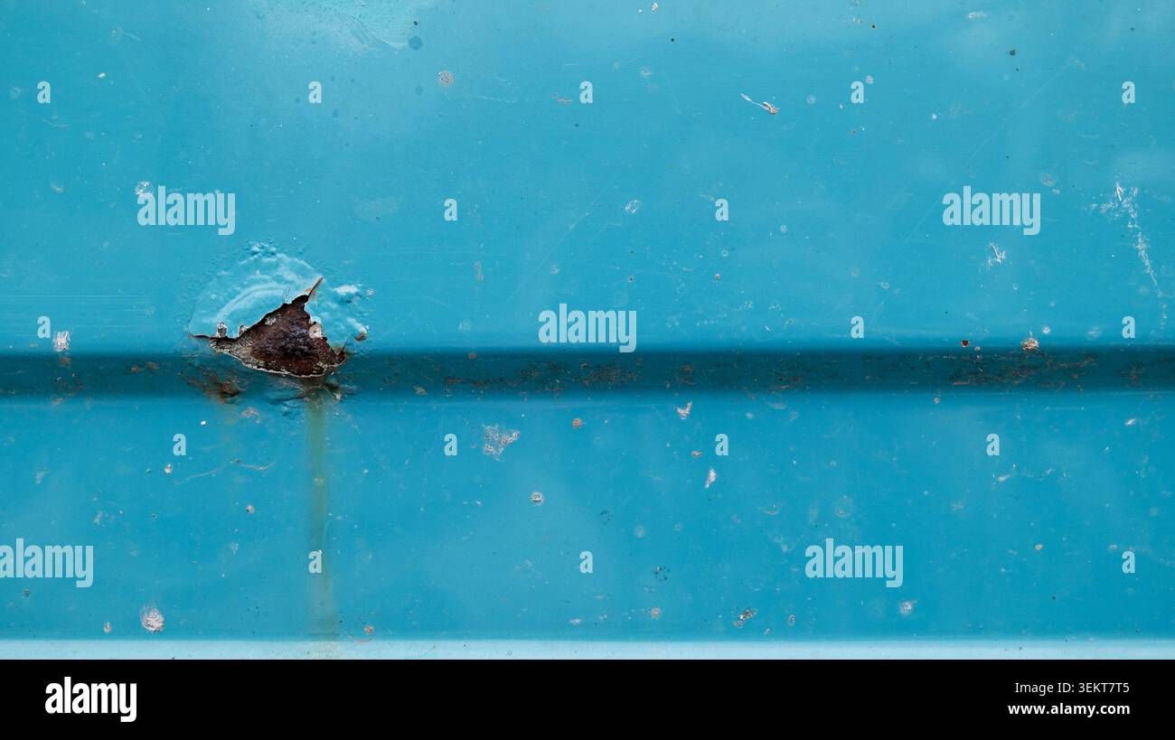 Rust hole on blue metal surface Stock Photo