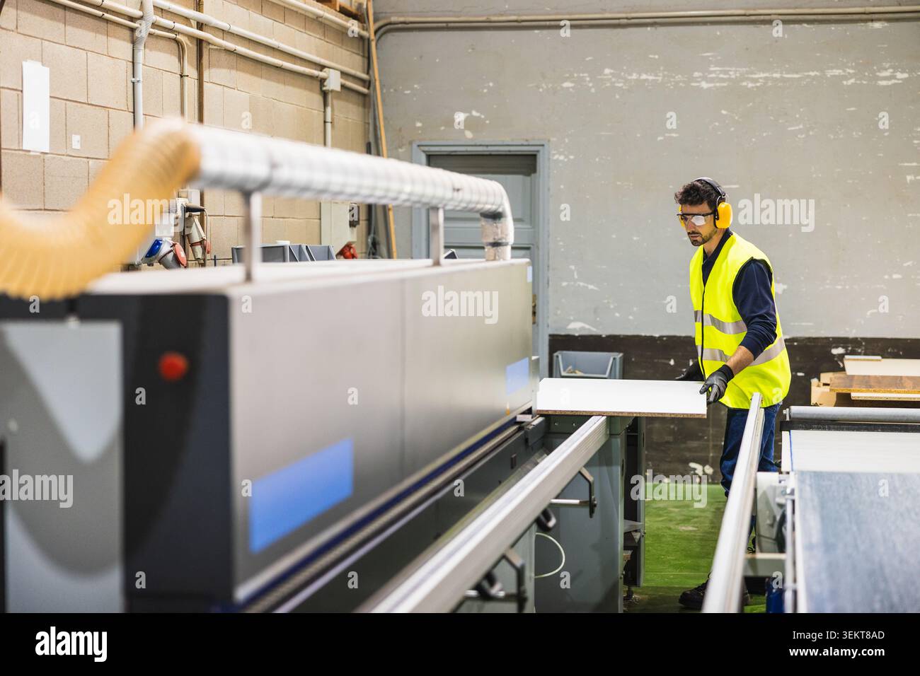 Woodworker operating industrial machine in manufacturing workshop Stock Photo