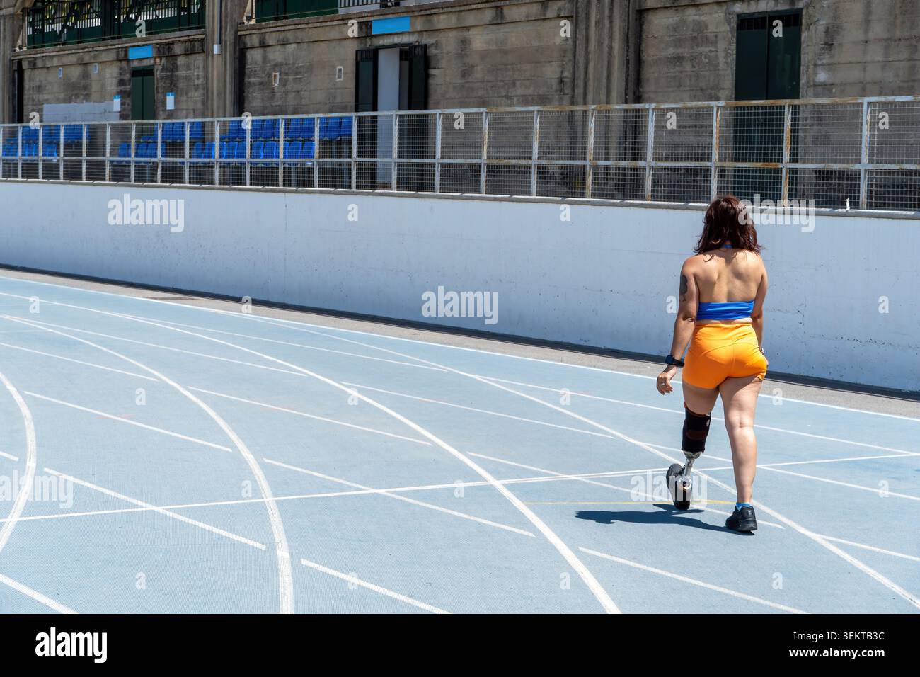 Woman with prosthetic leg walking on track Stock Photo