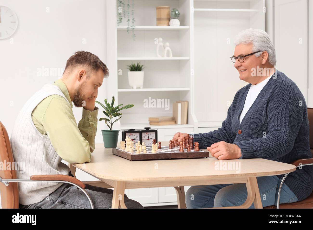 Senior man and his son playing chess at home Stock Photo