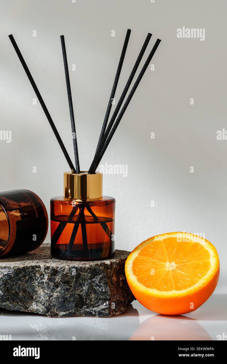 Scent diffuser beside orange on stone surface in bright light Stock Photo