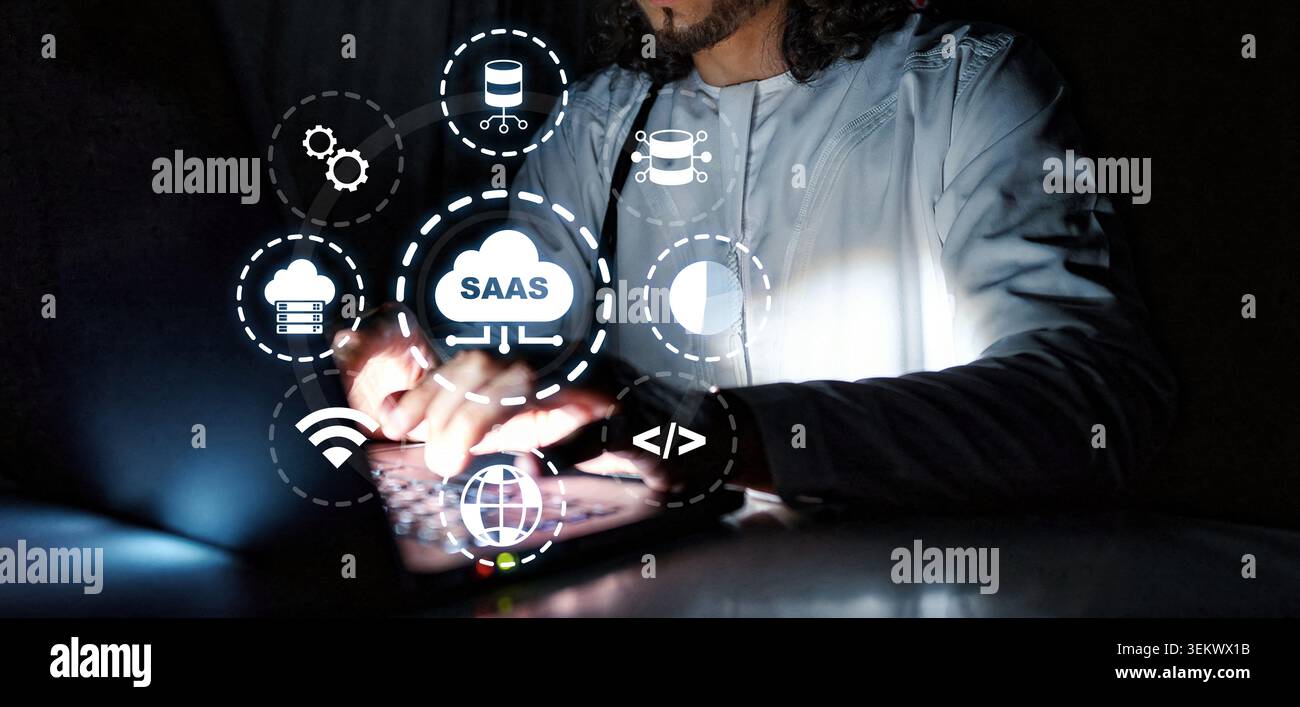 Working with Saas concepts in a dark environment while typing on a laptop Stock Photo