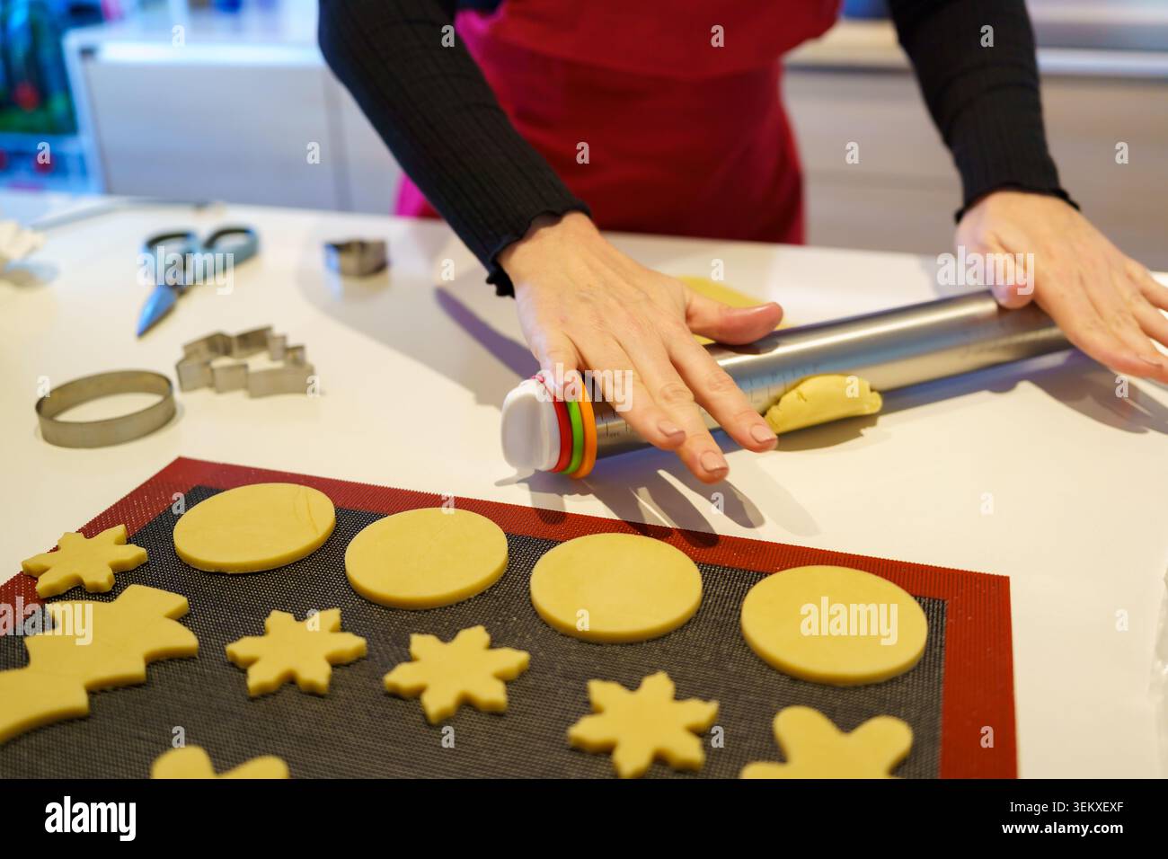 Hands rolling cookie dough with a rolling pin on a white counter Stock Photo