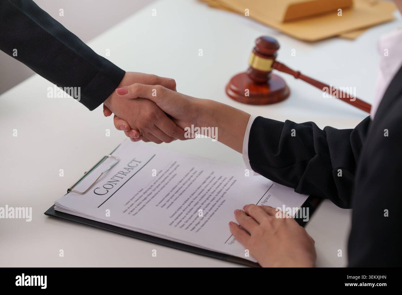 Business professionals shaking hands over signed contract Stock Photo