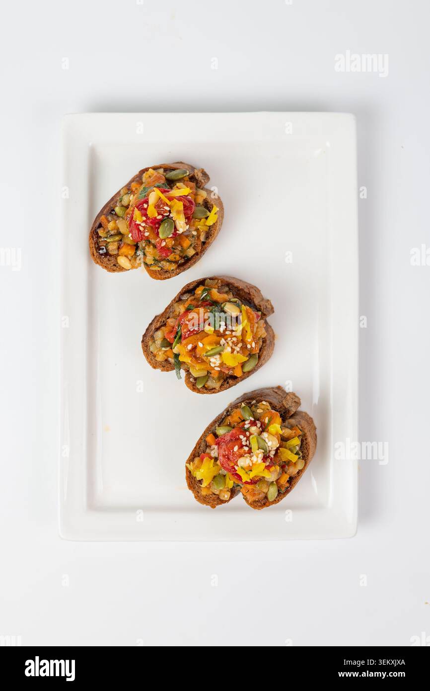 Top view flat lay of three vegetable bruschettas on white rectangular plate Stock Photo
