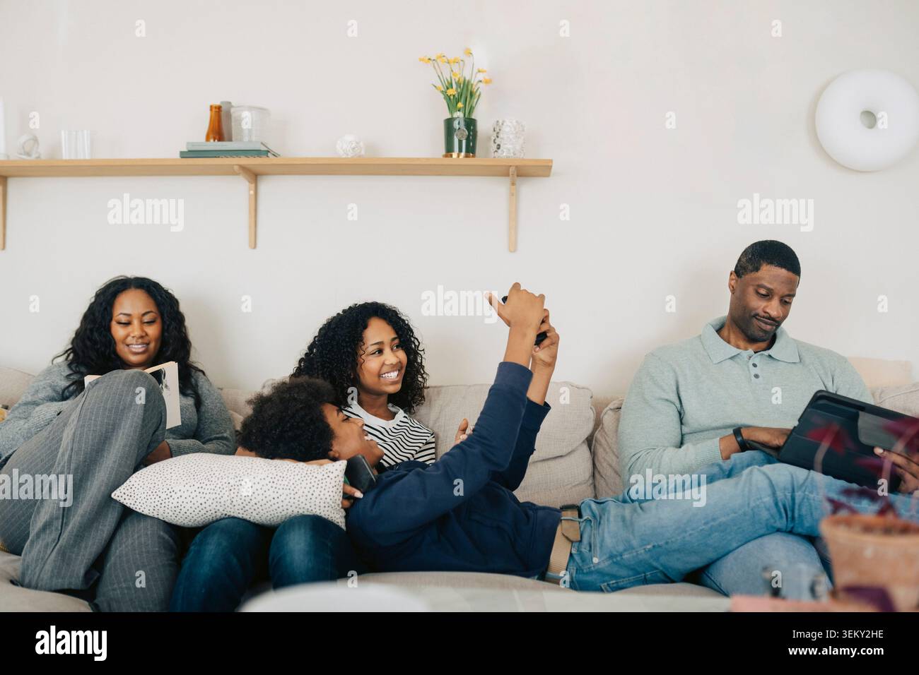 Happy family spending quality time together while using different electronic devices at home Stock Photo
