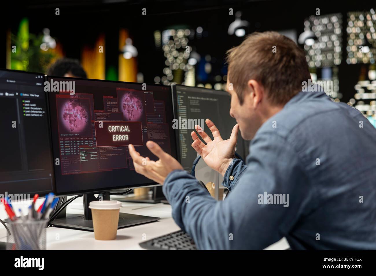 Engineer at office desk frustrated by critical error warning displayed on computer screen. Upset sech startup IT professional annoyed by computer bug affecting server network Stock Photo