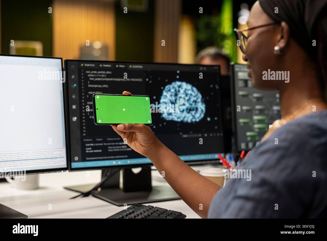 Engineer in tech startup office developing apps using AI automation on isolated screen smartphone. Worker debugging applications with artificial intelligence on mockup mobile phone Stock Photo