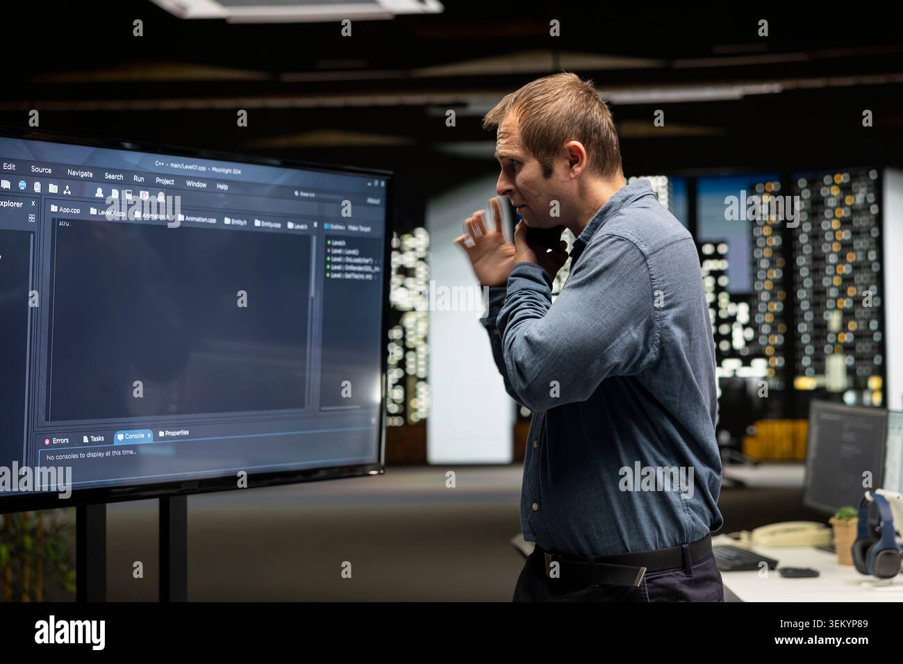 Startup manager looks at code written by workers, thinking how to leverage it to gain competitive edge. Supervisor looks at coding script on large screen, working on technological advancements Stock Photo