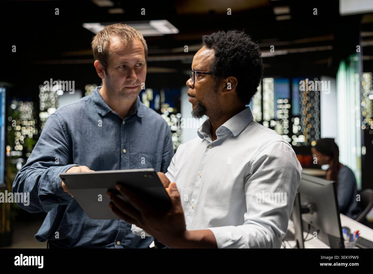 Team of engineers use tablet in tech startup office to develop apps using AI automation. Teamworking colleagues working on device, debugging applications with artificial intelligence Stock Photo