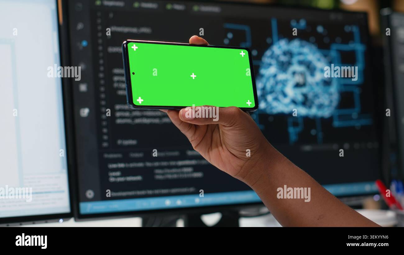 Isolated screen smartphone used by admin in office working to fix bugs in artificial intelligence system. Employee in tech startup using chroma key mockup mobile phone to watch videos Stock Photo