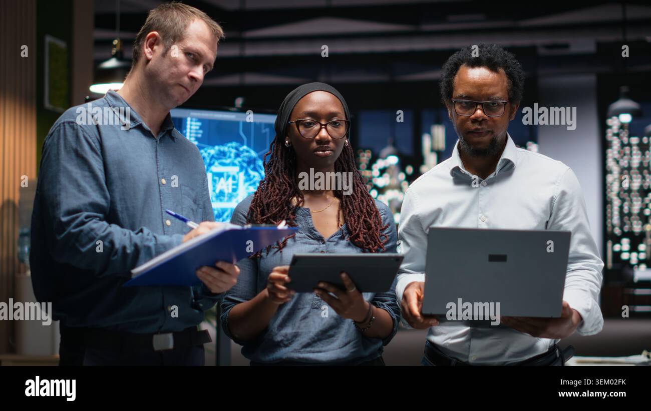 Portrait of engineering team developing artificial intelligence algorithms in high rise office. Teamworking colleagues debug 3D neural network brain models shown on screen Stock Photo