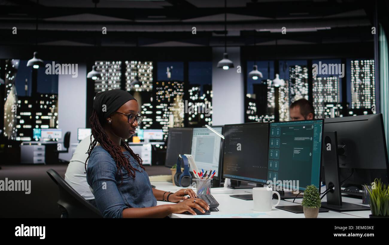 Female programmer using large language model application to get help with coding tasks. African american woman interacting with AI LLM chatbot PC GPT software on PC Stock Photo