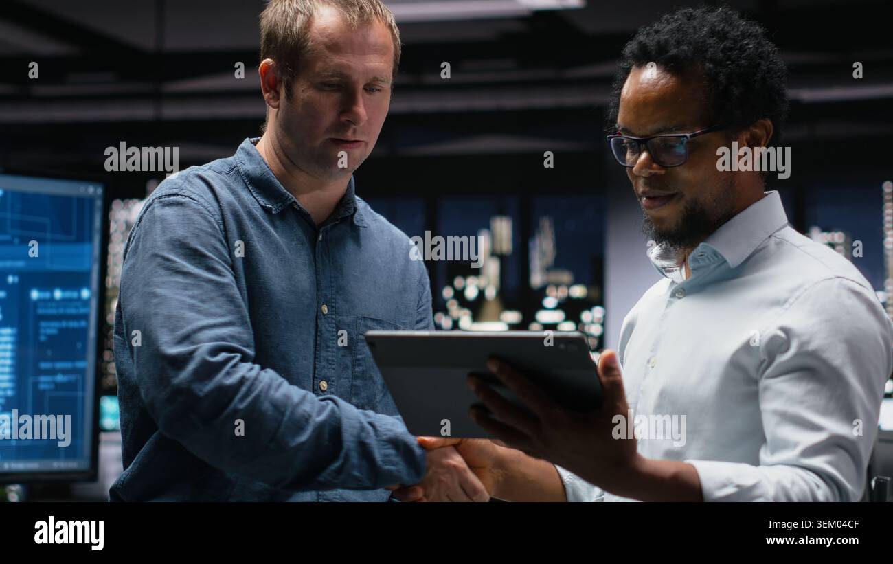 Engineering team using tablet in office, working with AI programming languages. Teamworking colleagues using device in company workplace to do artificial intelligence tech quality assurance Stock Photo