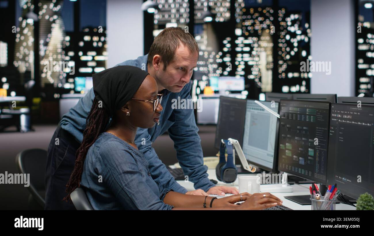 Manager supervising trainee typing code on computer, developing machine learning models to automate tasks in workspace. Team leader and intern writing programming language scripts on PC Stock Photo