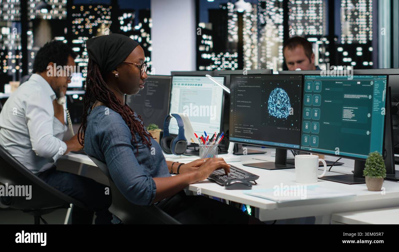Female programmer using large language model application to get help with coding tasks. African american woman interacting with AI LLM chatbot PC GPT software on PC Stock Photo