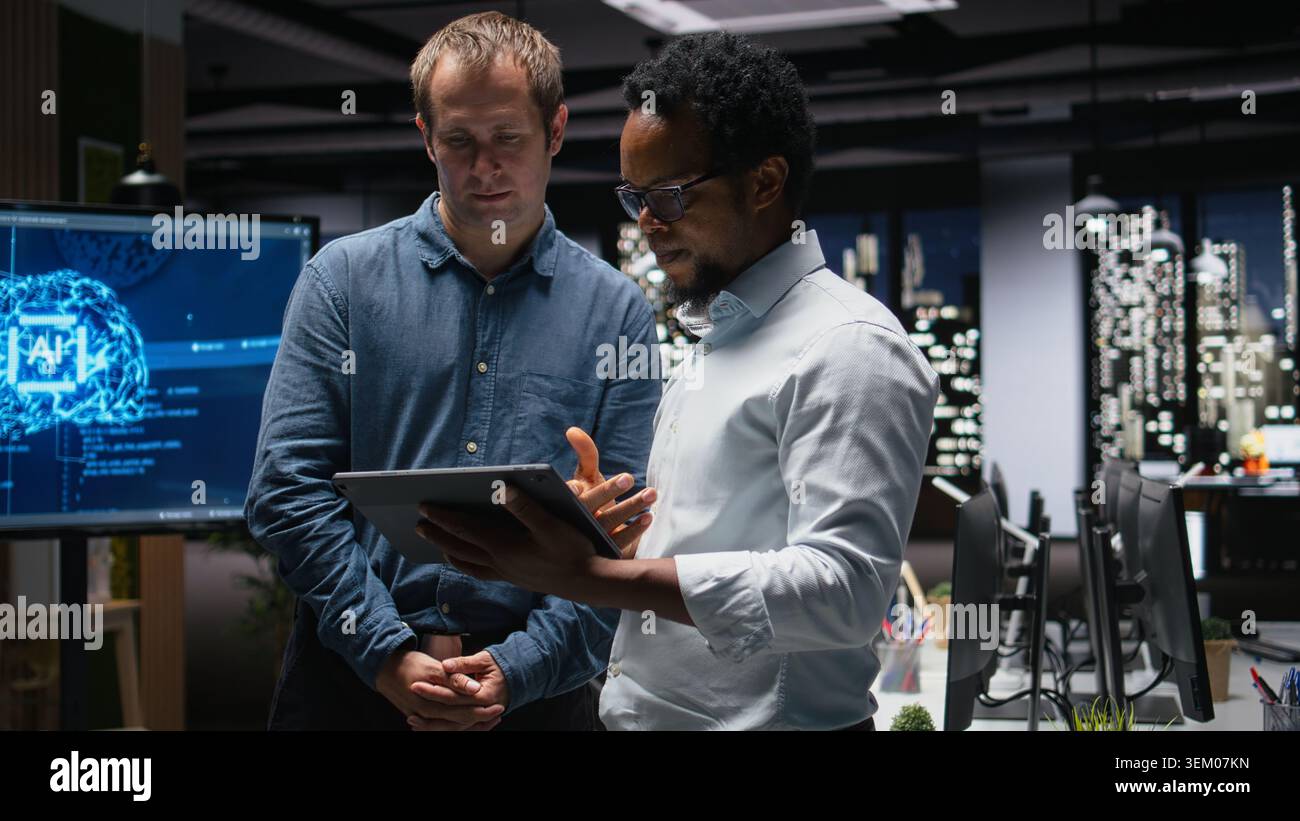 Programmers in office analyzing machine learning algorithms to prevent AI model errors. Colleagues reviewing code logic to improve artificial intelligence prediction accuracy Stock Photo
