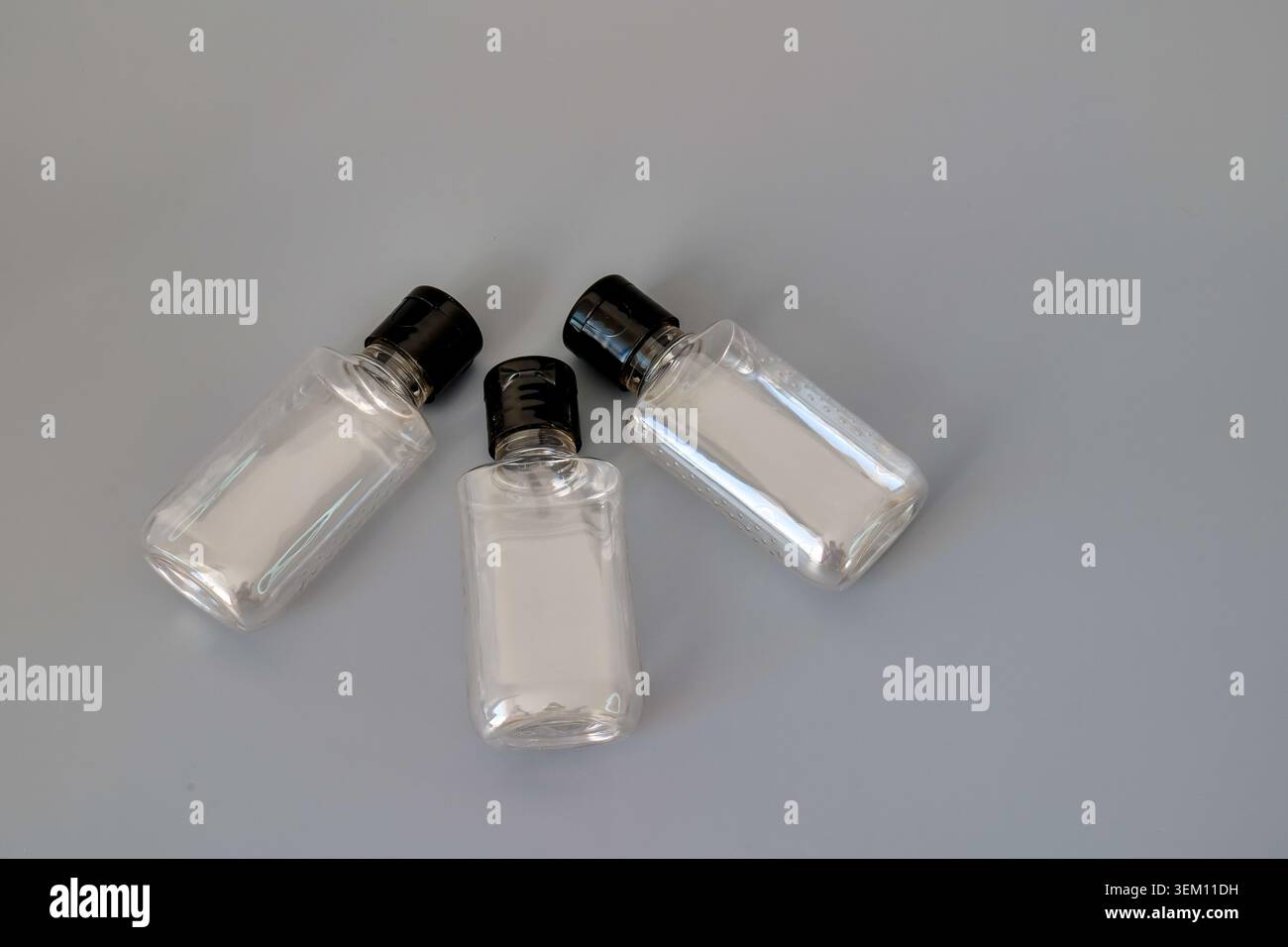 Three clear plastic bottles with black caps on a gray background Stock Photo