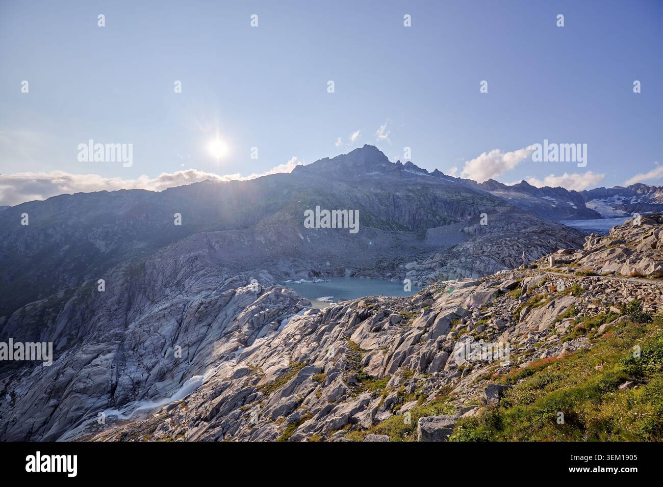 A rugged mountain range is lit by low sunlight under a dramatic cloudy sky. Stock Photo