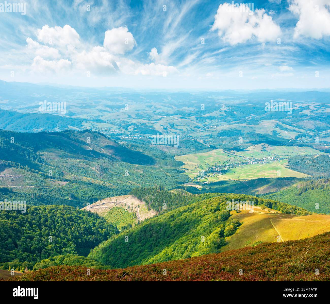 mountainous countryside scenery in the afternoon. view of cloudy sky above the valley. colorful meadows and trees on hill in dappled light. beautiful Stock Photo