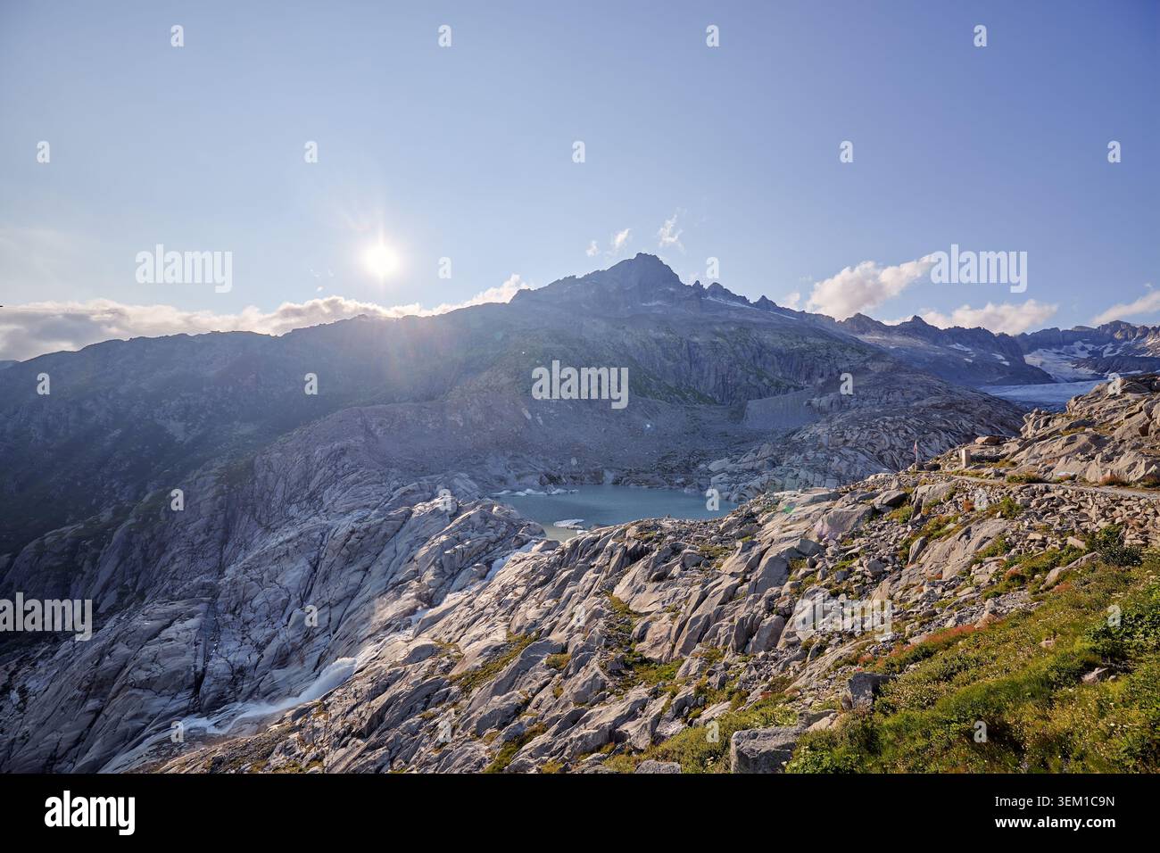 A rugged mountain range is lit by low sunlight under a dramatic cloudy sky. Stock Photo