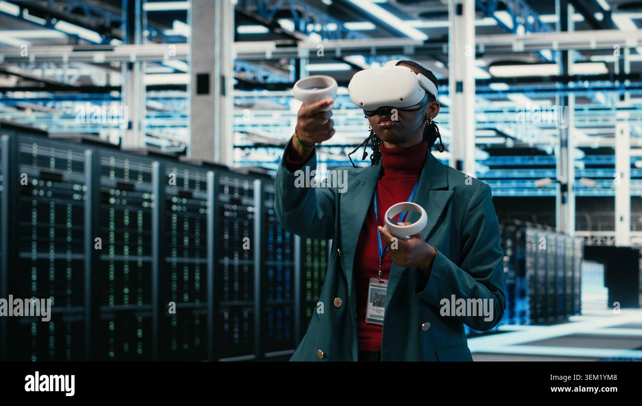 Data center system administrator uses VR headset gear and AR simulation to manage database storage rigs. Cloud computing server room worker uses virtual reality technology VFX visualization, camera B Stock Photo