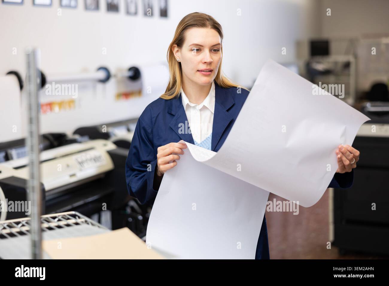 Print worker controlling printing process on modern offset machine in print shop Stock Photo