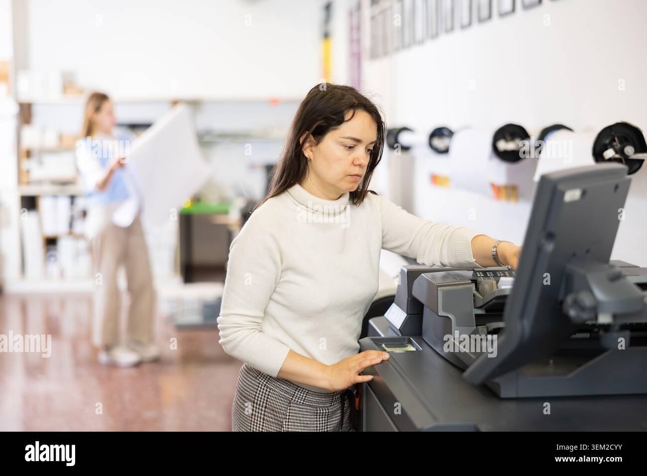 Technician operator calibrating plotter machine, typing on computer keyboard Stock Photo