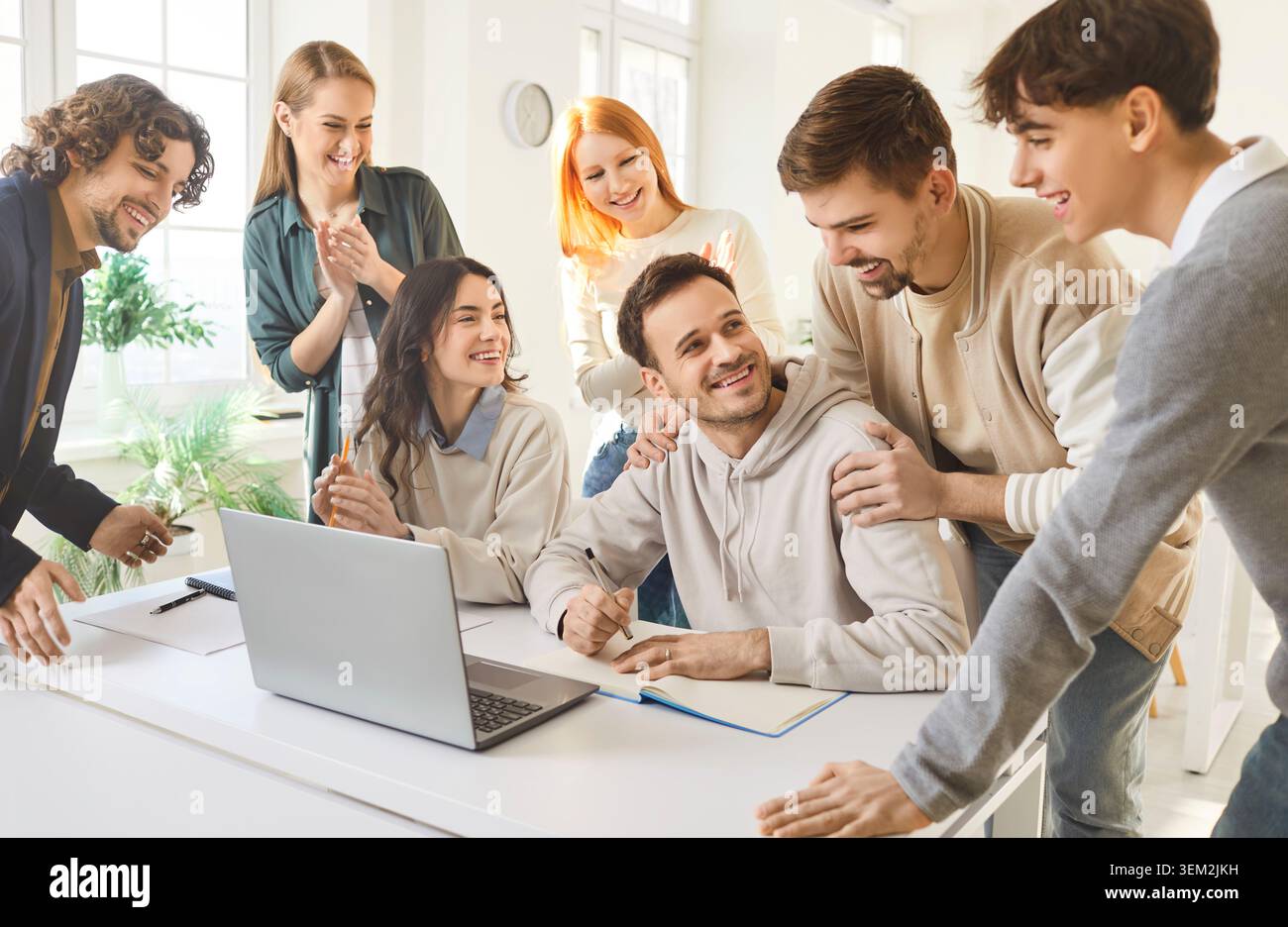 Diverse students collaborating on group project with laptop in bright study space Stock Photo