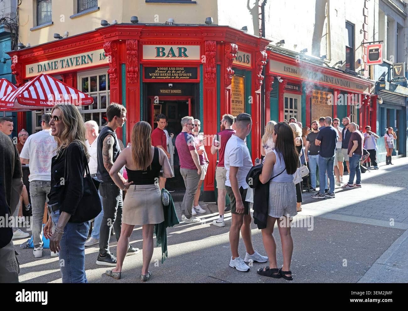 Happy summer crowds outside The Dame Tavern on Dame Court, Dublin 2, enjoying sunny warm outdoor hospitality in the city centre Stock Photo