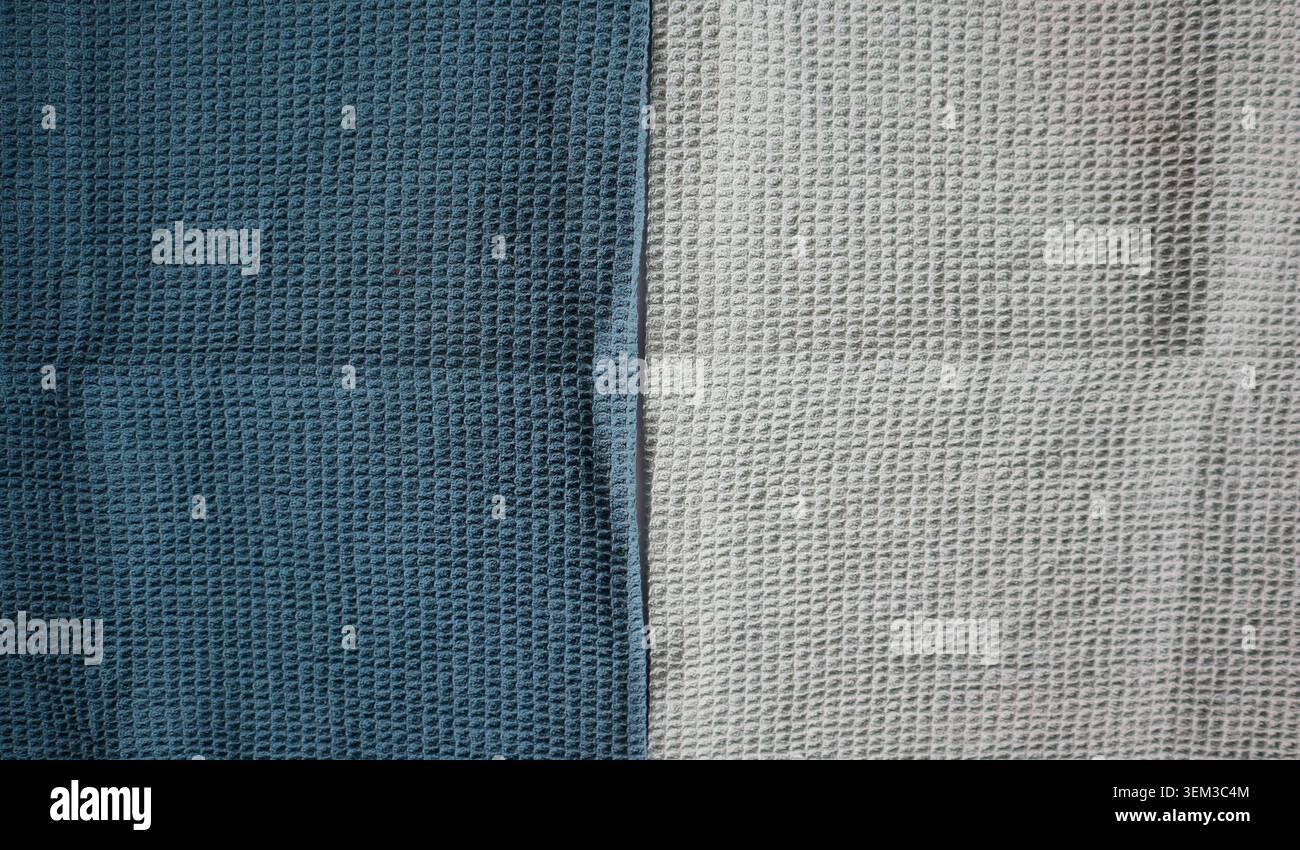 Two pieces of textured cloth are arranged side by side on a flat surface. One cloth is dark blue, and the other is light gray, showing their unique pa Stock Photo