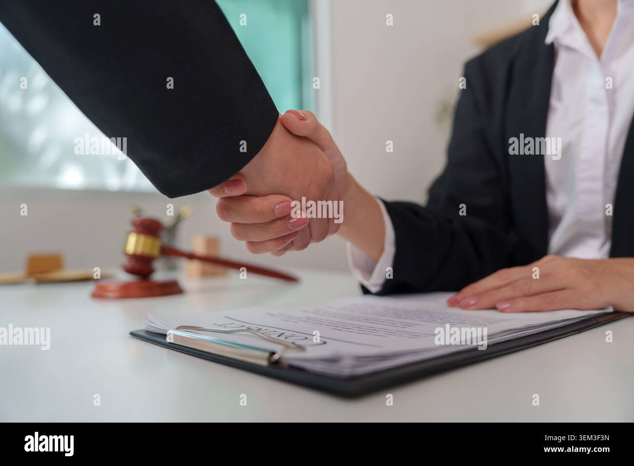 Business professionals shaking hands over signed contract Stock Photo