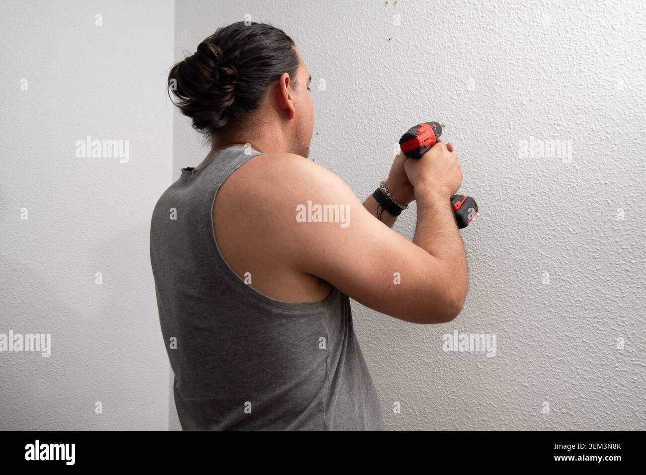 Man using power drill, making hole in wall for home improvement Stock Photo