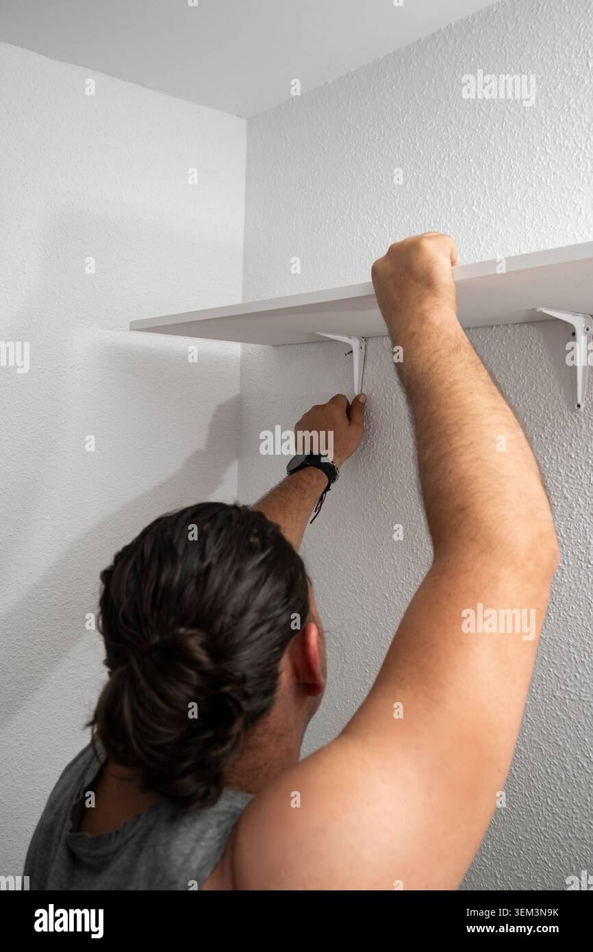Man installing shelf brackets during home improvement project Stock Photo