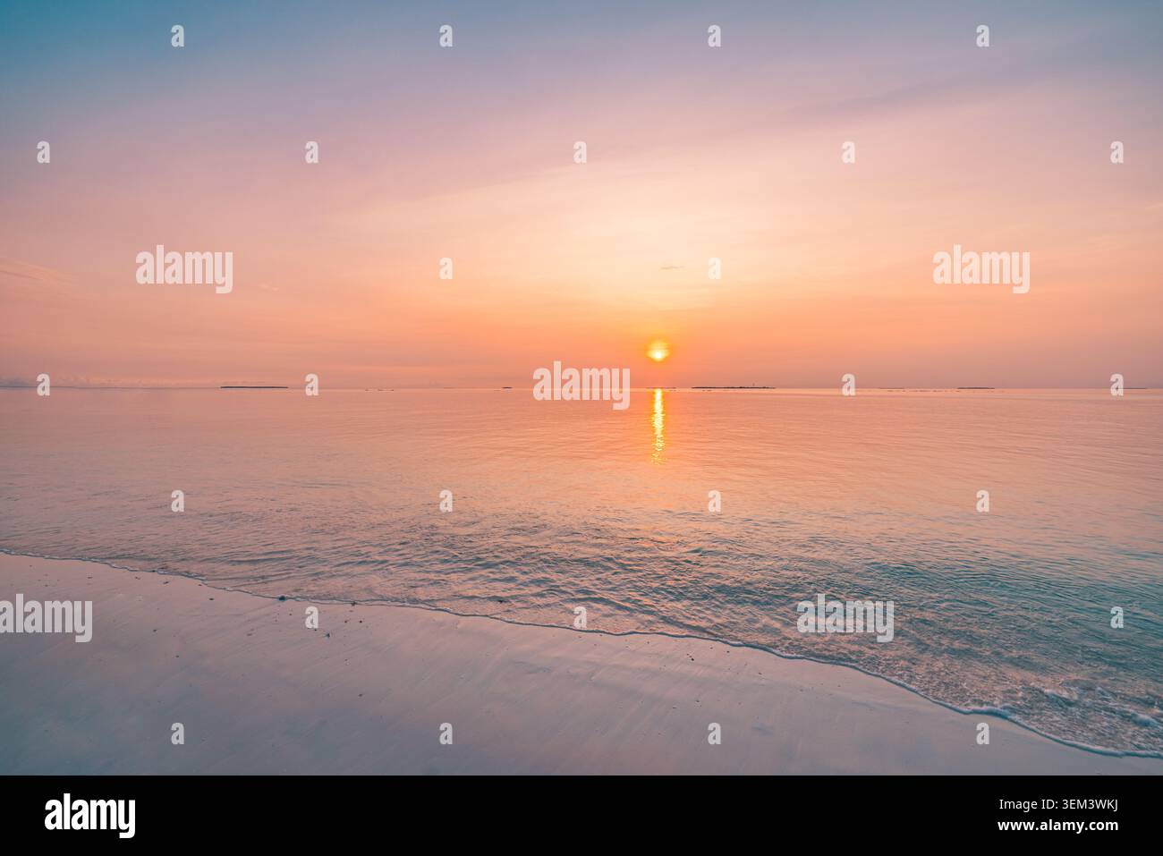 Golden sunset sun setting over calm tropical sea at beach shore horizon. Warm glowing ocean. Summer vacation travel holiday paradise scenic honeymoon Stock Photo