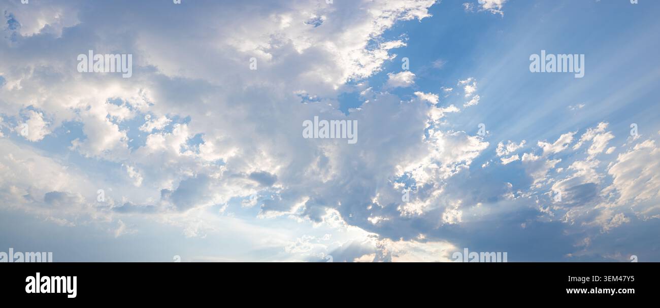 Heavenly sun rays breaking through dramatic clouds in wide panoramic sky. Sunbeams light natural cloudscape. Spiritual hope background copy space Stock Photo