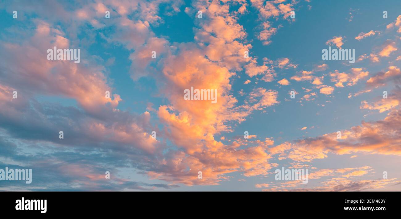Pastel pink orange sunset clouds drifting across soft blue evening sky. Dramatic cloudscape natural backdrop. Peaceful heaven background copy space Stock Photo