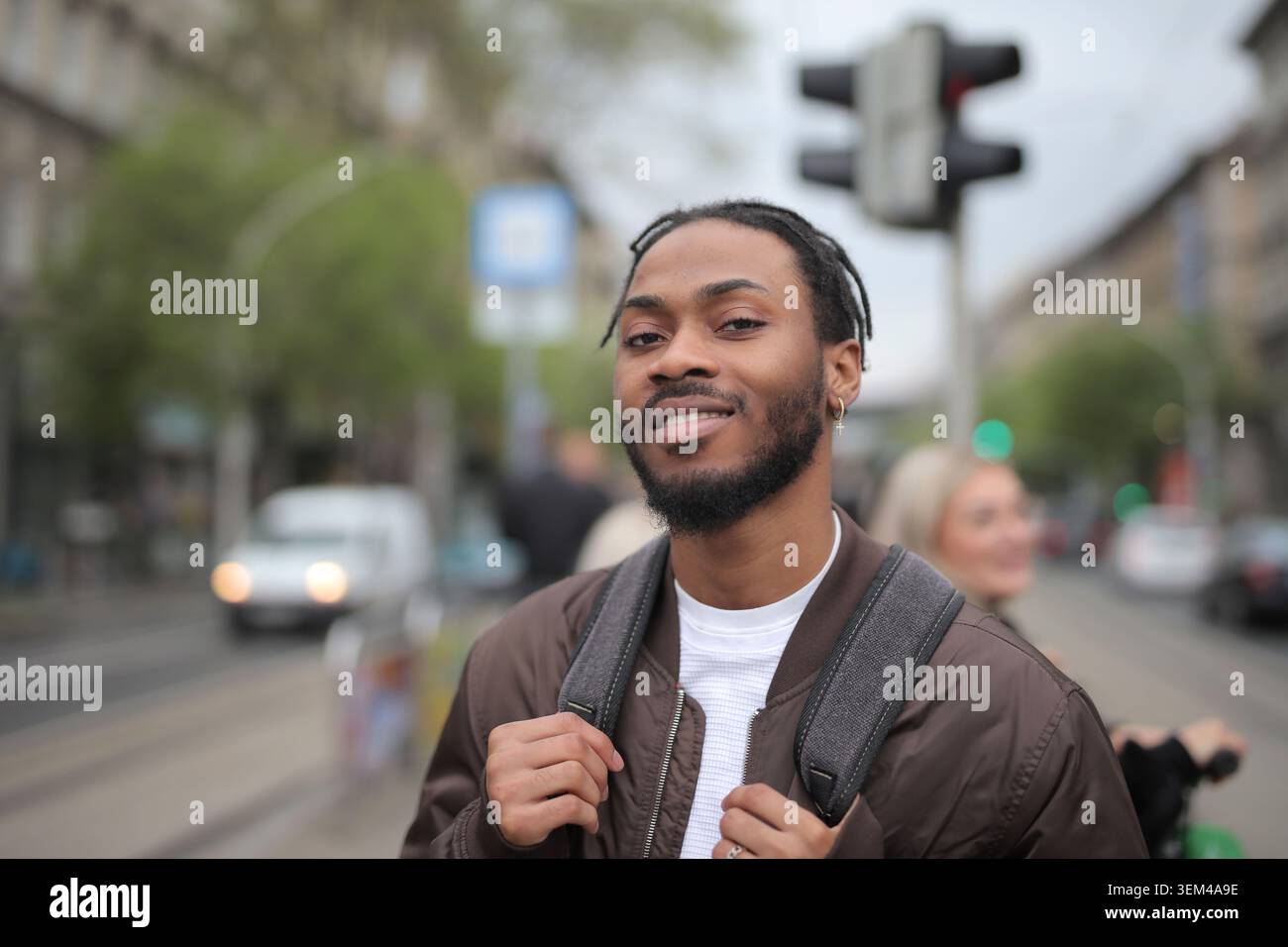 Young Black man with backpack smiling on street Stock Photo