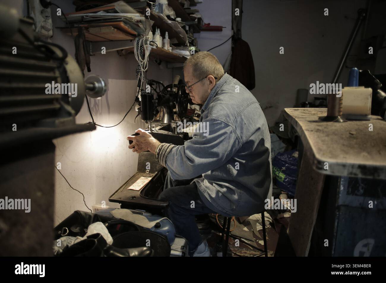 Elderly Asian artisan repairing a shoe in his workshop Stock Photo