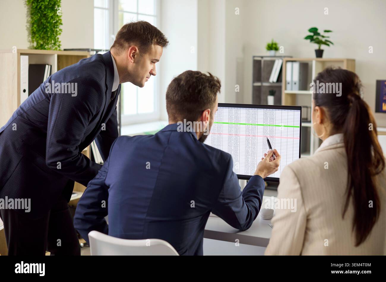 Managers review project data on computer, planning tasks and strategy in office Stock Photo