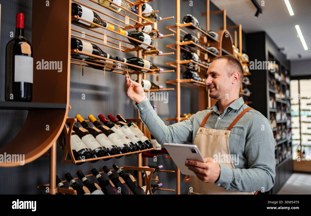 Sommelier checking wine inventory in a modern shop using a digital tablet Stock Photo