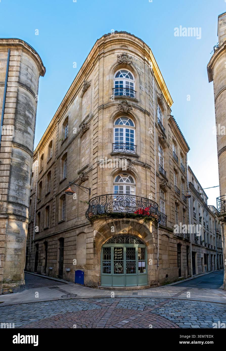A beautiful stone corner building with arched windows, ornate wrought iron balconies, and a curved entrance,  Bordeaux old town, France Stock Photo