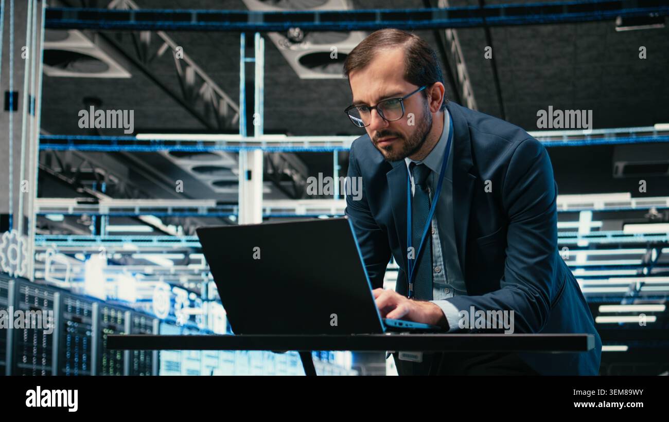 Data center admin typing on laptop keyboard, doing resource optimization using software. Server farm IT specialist using notebook program to upgrade hardware supercomputers, camera A Stock Photo